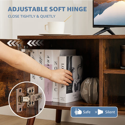 Wooden cabinet with a hand opening a shelf, showing an adjustable soft hinge, with books and a TV in the background.