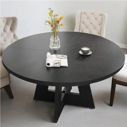 Round black dining table with a vase of flowers, coffee cup, and magazine in a modern living room.