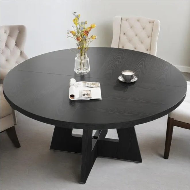 Round black dining table with a vase of flowers, coffee cup, and magazine in a modern living room.