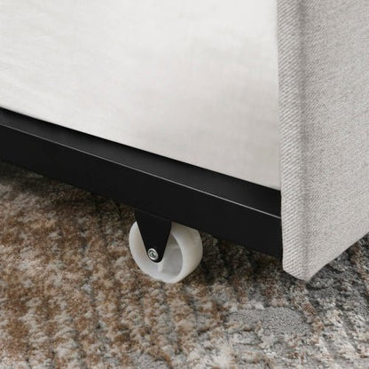 Close-up of a bed with wheels on a carpeted floor