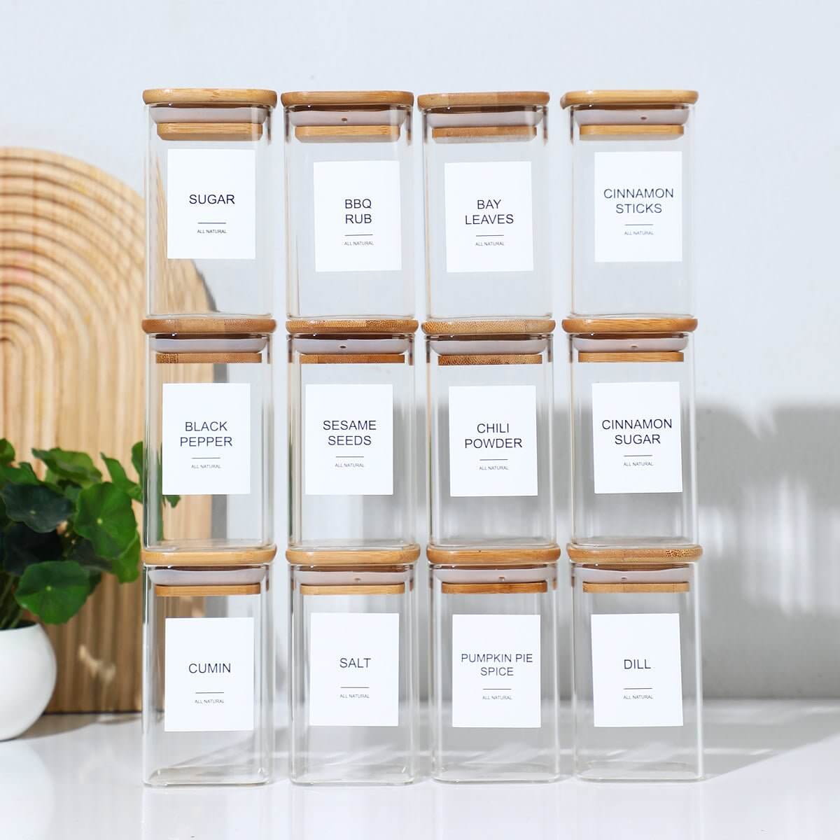 Square glass spice jars with wooden lids and labeled stickers for organization.
