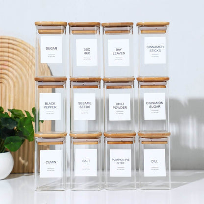 Square glass spice jars with wooden lids and labeled stickers for organization.