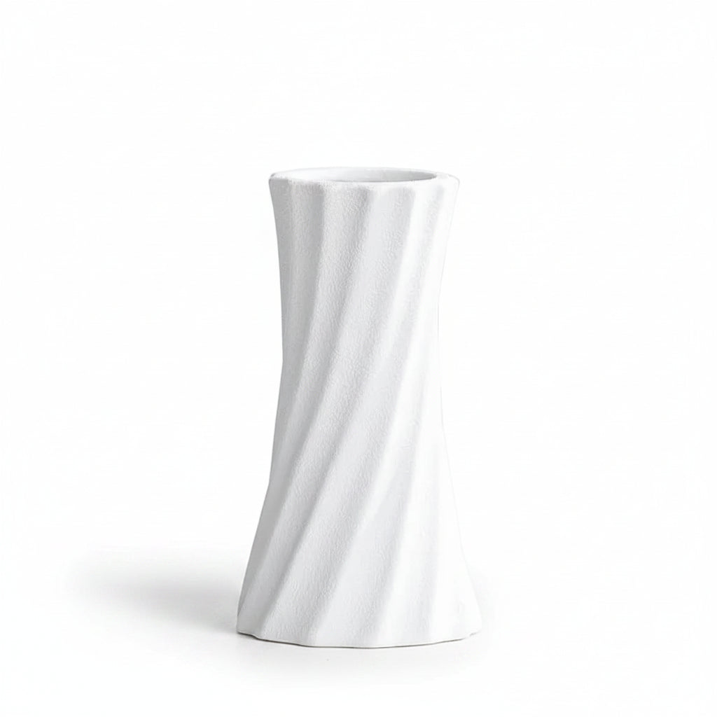 A white textured ceramic vase with a twisted spiral design, shown on a light gray surface with a soft shadow. Text in the upper left corner reads '6.