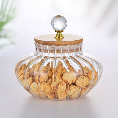 Glass jar with wooden lid and crystal knob filled with snacks on a white background