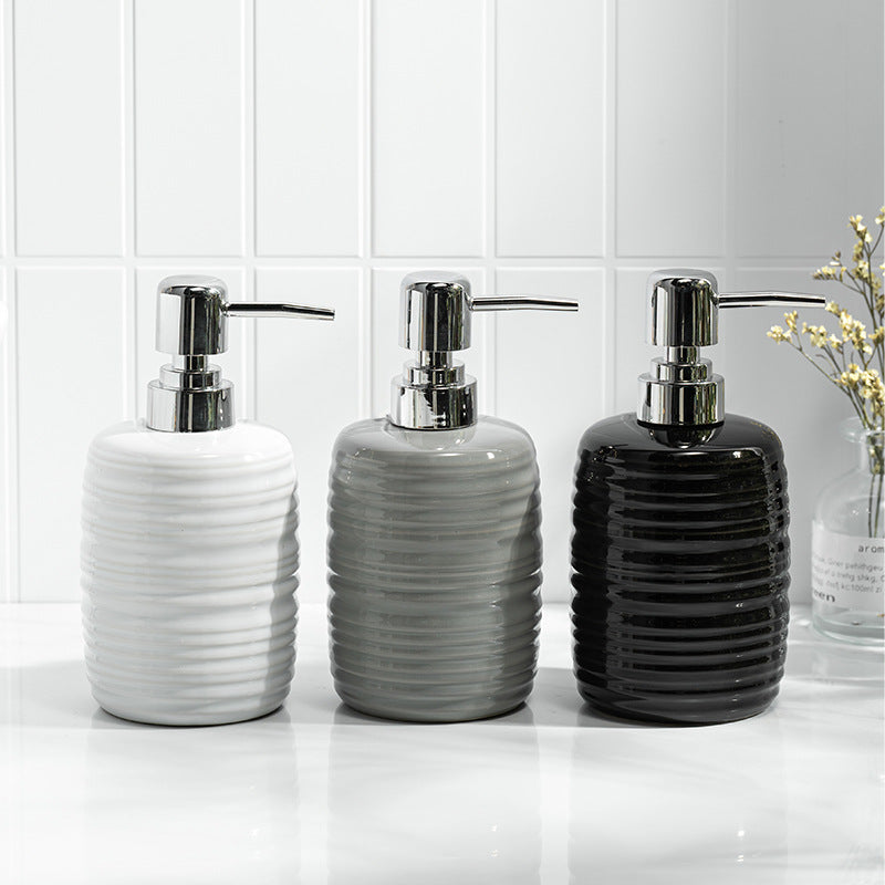 Three ceramic soap dispensers with silver pumps on a bathroom counter.