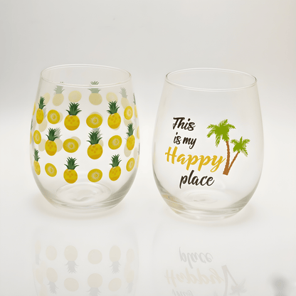 Two stemless wine glasses with pineapple pattern and 'Happy Place' text on a white background